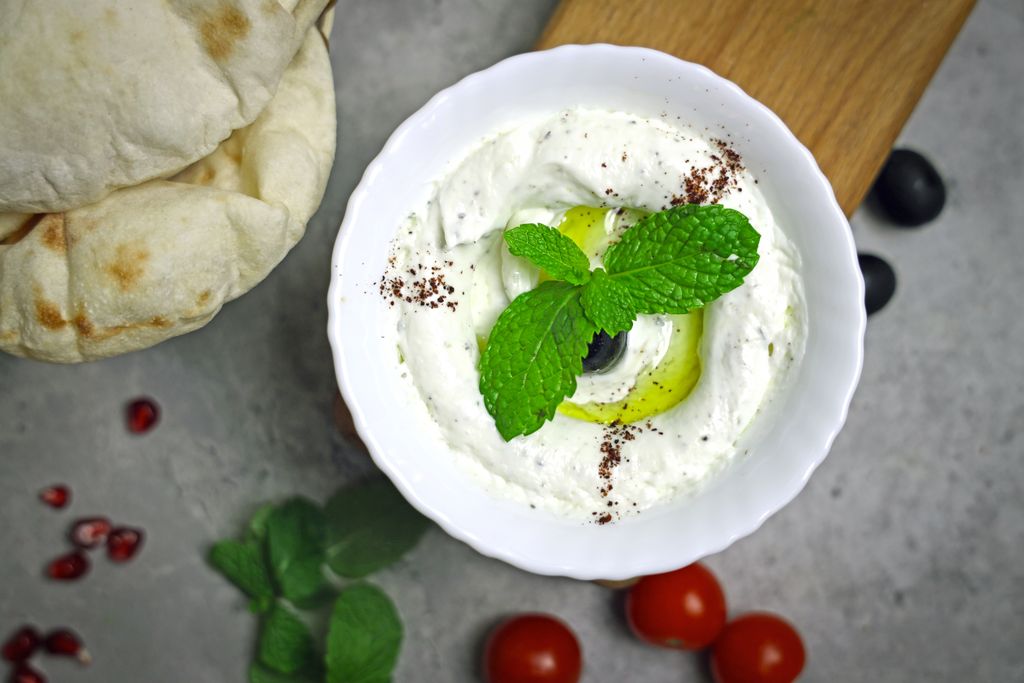 Photo by Shameel mukkath Creamy Greek yogurt dip garnished with mint and olive, perfect for a healthy snack.
