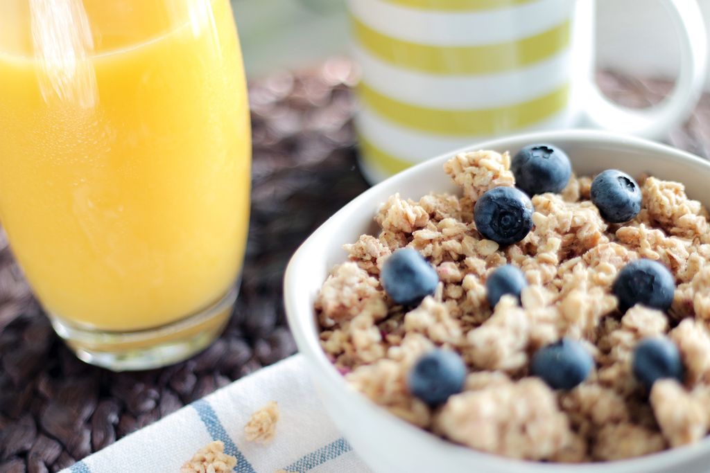 Photo by JÉSHOOTS Delicious breakfast bowl with muesli, blueberries, and fresh orange juice, perfect for a healthy start.